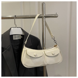 Detail of retro off-white shoulder bag with double pockets hanging on metal stand