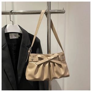 Detail van beige geplooide draagtas met strikaccent en zachte matte afwerking
