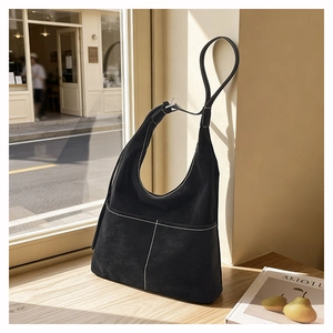 Detail of black suede hobo tote bag featuring contrast stitching and front pockets