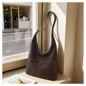 Detail of dark brown matte tote bag with contrast white stitching in natural light