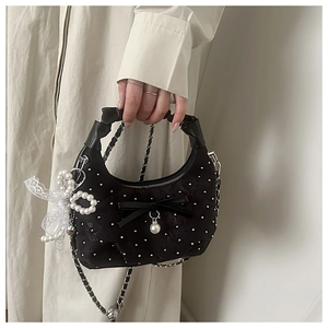 Detail view of black crescent bag with silver studs, lace bow, and pearl pendant