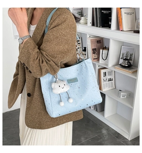 Dettaglio borsa tote azzurra con stelle, catena dorata e ciondolo a forma di nuvola
