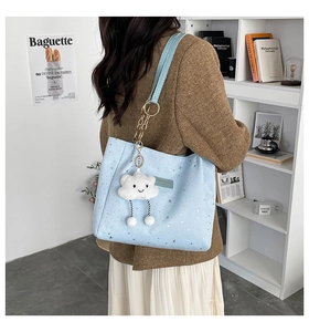 Dettaglio della borsa tote azzurra con stampa a stelle e grazioso ciondolo a nuvola sulla tracolla
