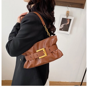 Détail d'un sac à bandoulière marron avec large sangle et grande boucle dorée élégante