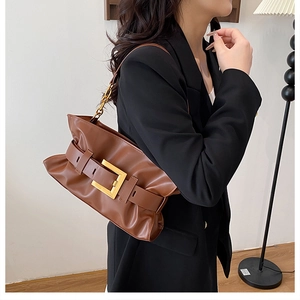 Détail du sac plissé marron avec une grande boucle dorée et une bandoulière en chaîne
