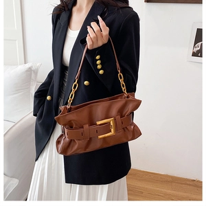 Détail d'un sac plissé marron avec boucle dorée et bandoulière en chaîne métallique