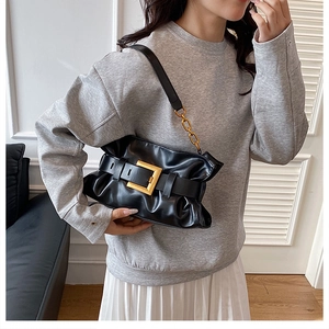 Détail d'un sac cabas en cuir souple noir avec une grande boucle dorée sur un mannequin