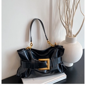Détail du sac nuage plissé noir avec grande boucle dorée et bandoulière en chaîne