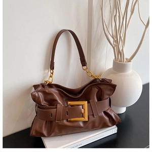 Détail du sac à bandoulière marron plissé avec une grande boucle dorée et chaîne métal
