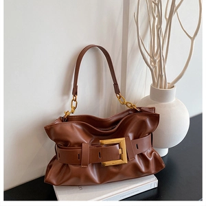 Détail d'un sac nuage plissé marron avec boucle dorée et anse en chaîne chic