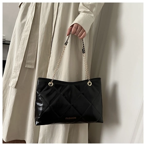 Détail d'un sac bandoulière matelassé noir avec chaîne dorée et lettrage Fashion