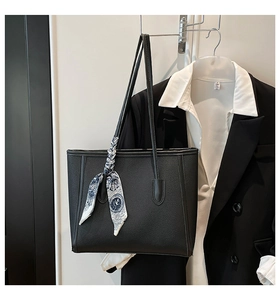 Close-up of a black lychee texture tote bag with elegant floral scarf detail on hanger