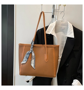 Close-up of brown litchi grain leather tote bag with a decorative floral silk scarf handle
