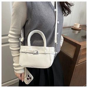 Close-up of a white mini handbag with silver buckle details and a slim shoulder strap
