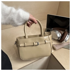 Detail of a beige PU leather tote bag with silver buckle in a modern office lifestyle setting