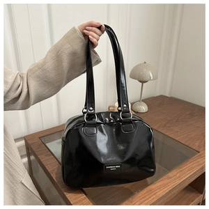 Dettaglio della borsa in vernice nera lucida con borchie argentate e manici eleganti
