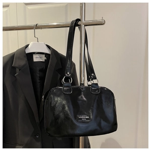 Vue détaillée du sac cabas noir brillant avec ferrures argentées et plaque logo en métal