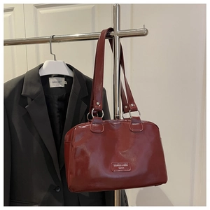 Détail du sac Boston en cuir verni rouge foncé avec boucles argentées et logo gravé