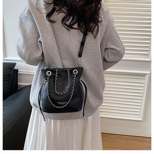 Detail of black bucket bag with silver chain handle and white brand logo print