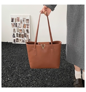 Nahaufnahme der braunen Ledertasche mit goldener V-Schnalle und strukturierter Oberfläche