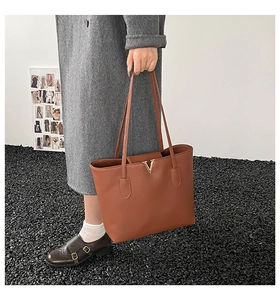 Detail der braunen Ledertasche mit goldenem V-Logo und langen Schultergriffen