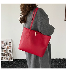 Detail of red pebbled leather tote bag with gold V-hardware and slim shoulder straps
