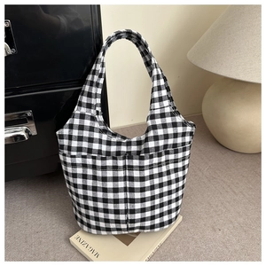 Detail of checkered canvas tote bag with front pocket placed on vintage books
