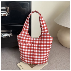 Macro detail of red and white gingham canvas tote bag with front pocket on a desk