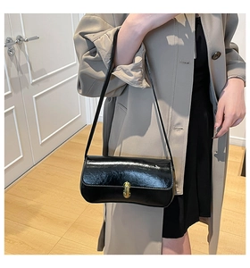 Detail der glänzenden schwarzen Baguette-Tasche mit goldenem Metallverschluss und Textur