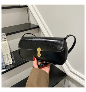Detail of glossy black leather handbag featuring a vintage gold cylindrical metal lock