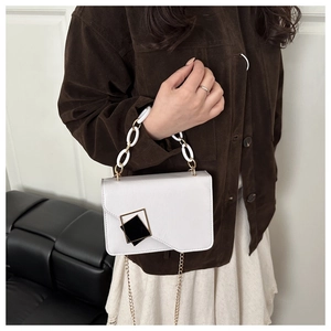 Detail of white leather handbag with black geometric clasp and acrylic chain handle