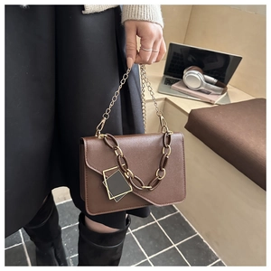 Detail of brown vintage flap bag with resin and gold chain strap in daily workspace