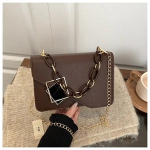 Detail of dark coffee flap bag with gold chain strap and decorative resin chain