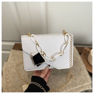 Close-up of white leather handbag featuring a chic gold chain and geometric charms