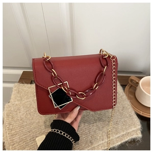 Close-up of red square crossbody bag with acrylic chain and geometric charm detail