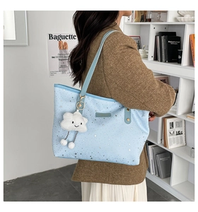 Close-up of light blue tote bag with silver star patterns and cloud plush pendant