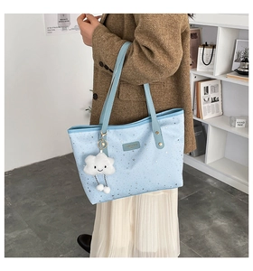 Close-up of light blue star-patterned tote bag with a cute white plush cloud charm