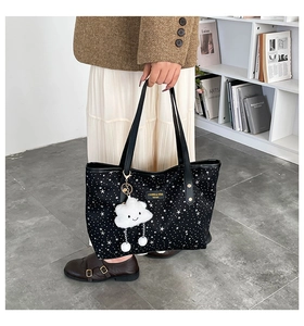 Detail of black tote bag with white star pattern and cute cloud plush charm accessory
