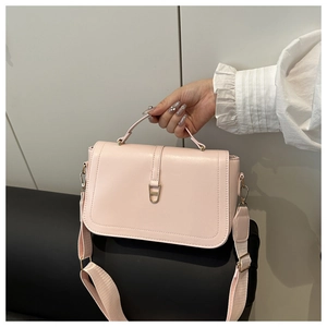 Detail van roze PU-leren vierkante tas met gouden slot en brede schouderriem