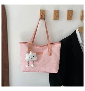 Detail of pink canvas tote bag with silver star prints and a plush cloud charm