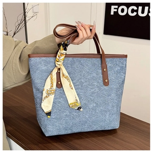 Detail of blue textured tote bag with brown leather handles and a stylish silk scarf