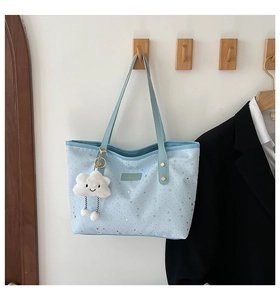 Detailed view of light blue tote bag with silver star prints and fluffy cloud charm