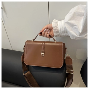 Detail van vintage bruine leren tas met gouden gesp en geweven schouderband