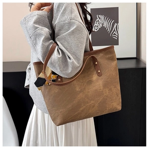 Close-up of brown canvas tote bag with leather handles and decorative geometric silk scarf