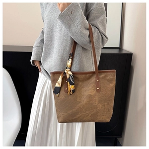 Brown tote bag detail with decorative printed silk scarf tied on a slim shoulder strap