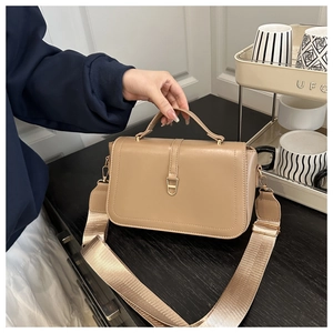 Detail van khaki zacht lederen crossbodytas met gouden D-gesp en brede geweven schouderriem