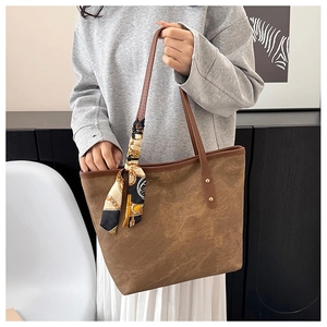 Detail of a brown large tote bag with silk scarf handle and golden rivet accents