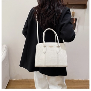 Detail of white crocodile textured tote bag with top handles and shoulder strap for women