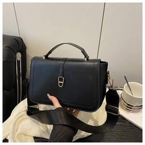 Macro detail of the golden D-ring buckle and matte leather texture on this black crossbody bag