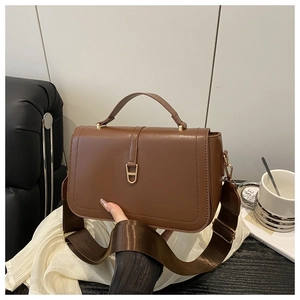 Detail of caramel brown leather handbag with gold geometric lock and wide nylon strap